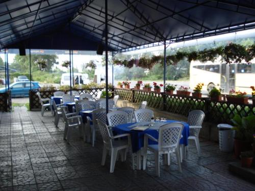 un groupe de tables et de chaises blanches avec des tables bleues dans l'établissement Complex Turistic Paralela'45, à Băicoi