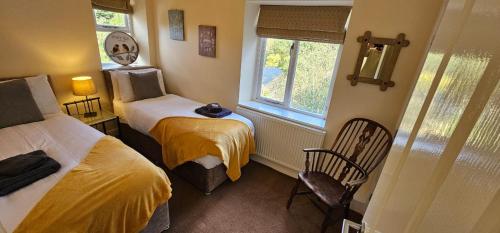 a small room with two beds and a window at Hazeldene Cottage in Holmfirth