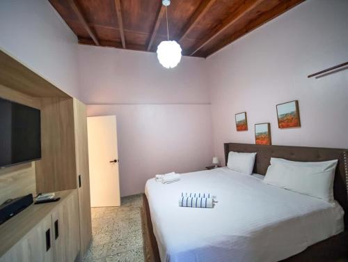 a bedroom with a white bed and a flat screen tv at Colonial 2BR Apartment 2 mins walk to beach in Sosúa