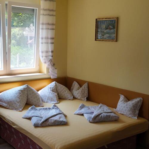 a bed with pillows on it in a room with a window at Villa Bella in Szántód