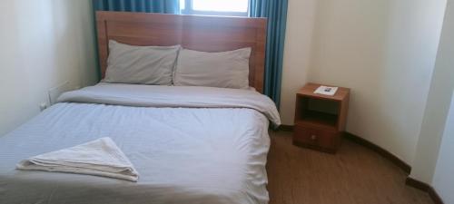łóżko z drewnianym zagłówkiem i szafką nocną w obiekcie Guest house w Addis Abebie
