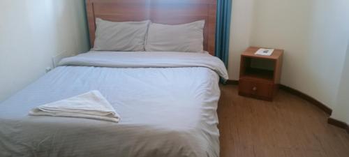 łóżko z drewnianym zagłówkiem i szafką nocną w obiekcie Guest house w Addis Abebie