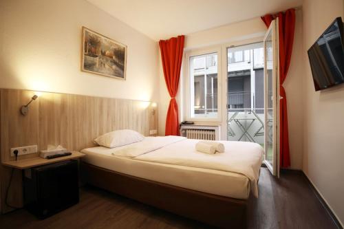 a small bedroom with a bed and a window at Hotel Paris in Düsseldorf