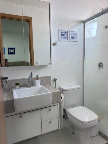 a bathroom with a sink and a toilet and a mirror at Apartamento 1001 in Guarapari