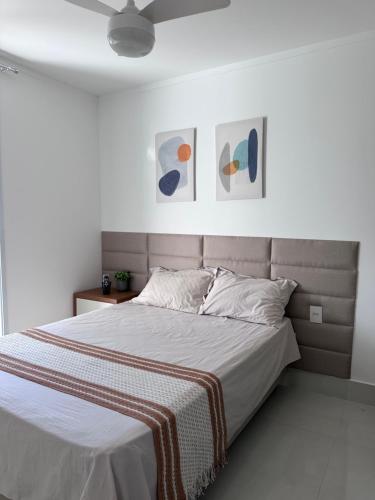 a bed in a bedroom with two pictures on the wall at Apartamento 1001 in Guarapari