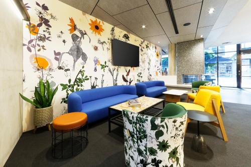 an office with a blue couch and a tv on a wall at Alpha Mosaic Hotel Fortitude Valley Brisbane in Brisbane