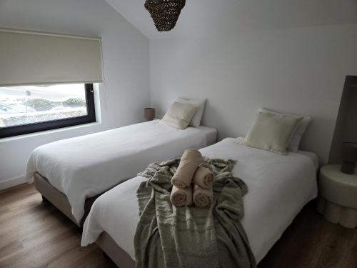 two beds in a bedroom with white walls and a window at Verliefd in Brustem in Sint-Truiden