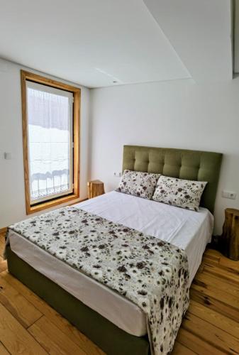 a large bed in a bedroom with a window at Casinha das Mimosas in Sanfins do Douro