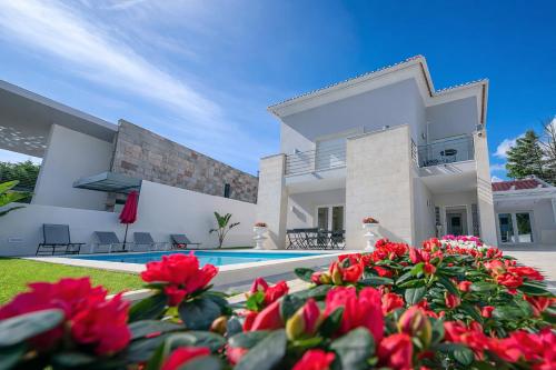 a villa with a swimming pool and red flowers at Sintra Dream Garden Villa near Cascais in Sintra
