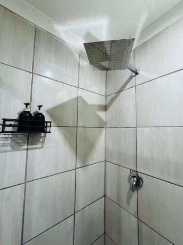 a bathroom with a shower with two jars on a shelf at Hei Stays Bachelor Apartment in Bronkhorstspruit