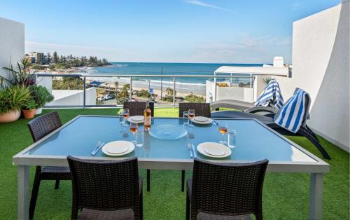 a table on a balcony with a view of the beach at Top Floor Unit With Private Rooftop Terrace in Caloundra