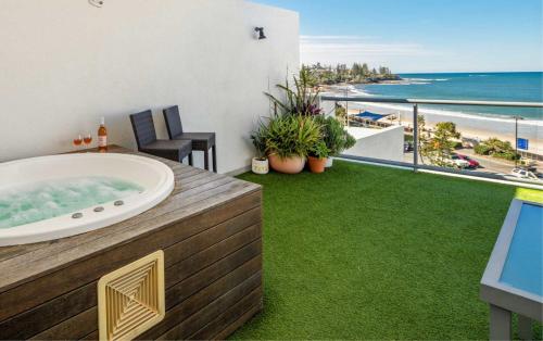 a bathroom with a tub and a balcony with the ocean at Top Floor Unit With Private Rooftop Terrace in Caloundra