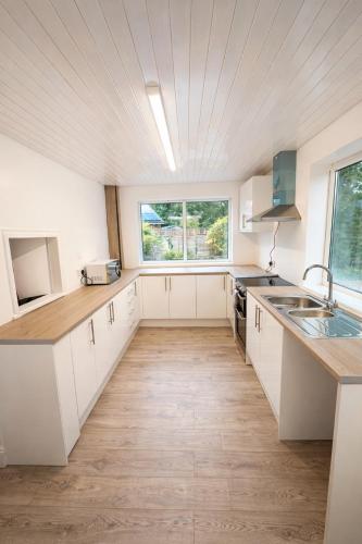 a kitchen with white cabinets and a large window at The City Gateway Villa in Manchester