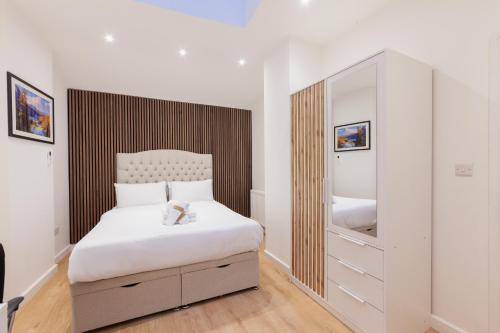 a bedroom with a white bed and a large mirror at Villas Apart Hotel in London