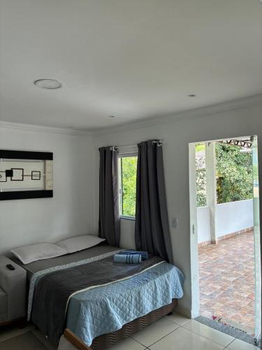 a bedroom with a bed and two windows at Refúgio Rio Soberbo in Guapimirim