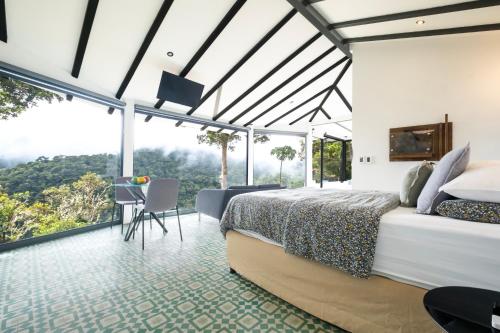 a bedroom with a bed and a large window at Dantica Cloud Forest Lodge in San Gerardo de Dota