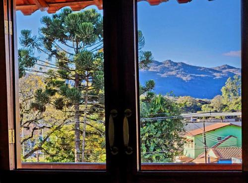 a window with a view of trees and a mountain at Pousada Dinhá Chica perto de Tiradentes e Bichinho in São João del Rei