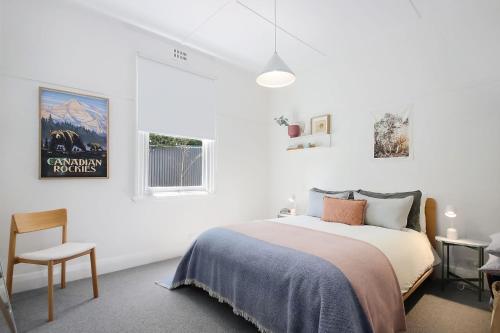 a white bedroom with a bed and a chair at The Gums, Beechworth in Beechworth