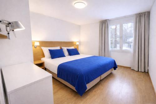 a bedroom with a bed with blue sheets and a window at Kylpyla Spa Villa Saimaan Harmonia in Imatra