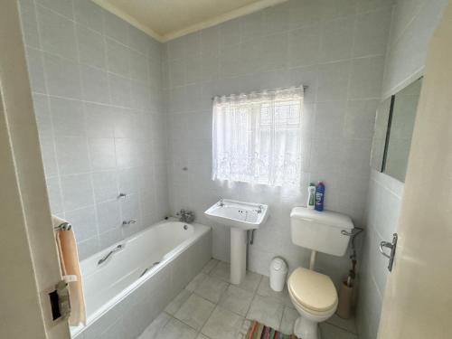 a bathroom with a tub and a toilet and a sink at SashMc Flair Guesthouse in Klerksdorp