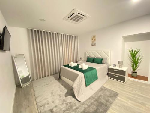 a bedroom with a white bed with a green blanket at Casa do Pelourinho in Arcos de Valdevez