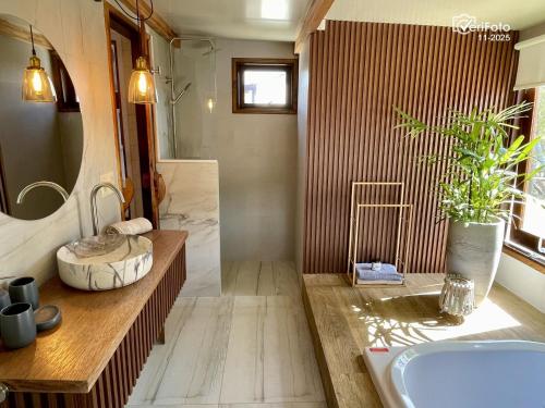a bathroom with a tub and a sink and a mirror at OHANA in Punta Del Diablo