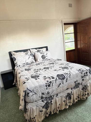 a bedroom with a bed with a black and white comforter at SashMc Flair Guesthouse in Klerksdorp