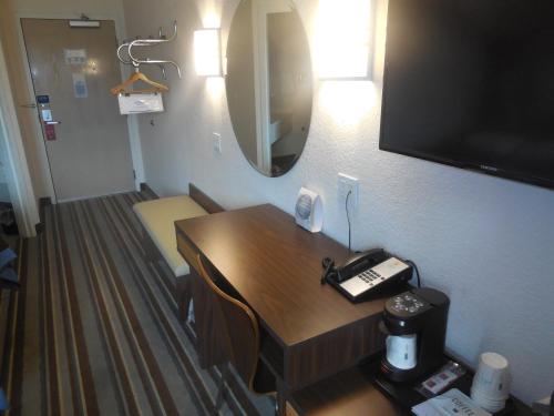 a room with a desk with a phone and a television at Super 8 by Wyndham Sault Ste. Marie in Sault Ste. Marie