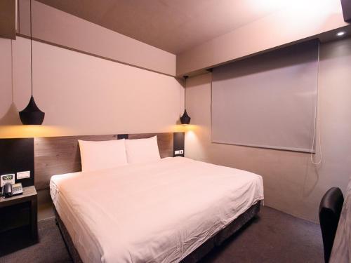 a bedroom with a white bed and a projection screen at Kiwi Express Hotel - Jiuru Rd in Kaohsiung
