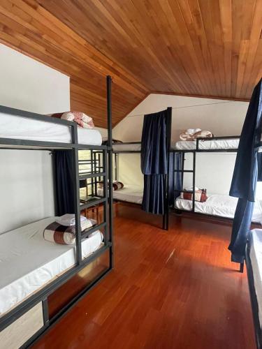 a room with three bunk beds and a wooden ceiling at Hostal Otro Mundo in Pasto
