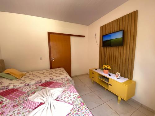 a bedroom with a bed and a tv on the wall at Casa Becker in Laranjeiras do Sul