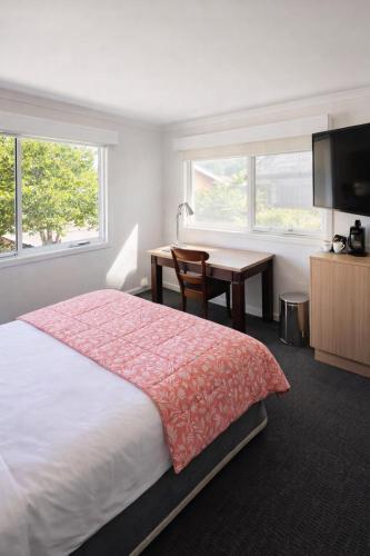 a bedroom with a bed and a desk and a television at The Dannebrog Lodge in Devonport