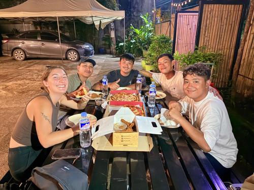 a group of people sitting around a table eating pizza at Goofy Ants Hostel in Puerto Princesa City