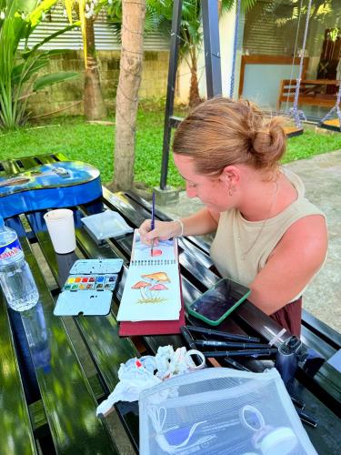 a woman painting a picture on a table at Goofy Ants Hostel in Puerto Princesa City