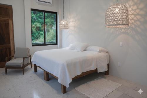 a bedroom with a bed and a chair and a window at Casa Azul, Oceanfront Estate with Rooftop Deck in Yelapa