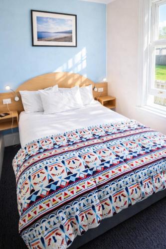 a bedroom with a bed with a colorful quilt on it at The Dannebrog Lodge in Devonport