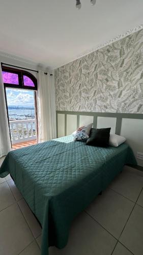 a bedroom with a bed with a green comforter and a window at Mirante Luz Floripa in Florianópolis