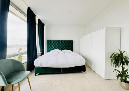 a bedroom with a bed and a green chair at Rheinpanorama Penthouse Neuss Düsseldorf in Neuss