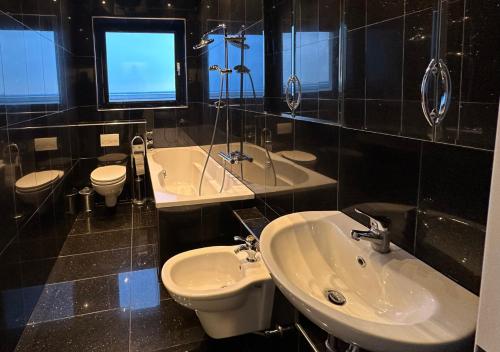 a bathroom with two sinks and a toilet and a tub at Rheinpanorama Penthouse Neuss Düsseldorf in Neuss