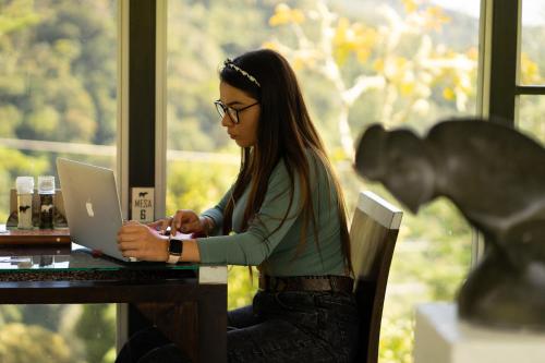 a woman sitting at a table using a laptop computer at Dantica Cloud Forest Lodge in San Gerardo de Dota