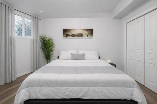a white bedroom with a large bed and a window at Bright 2BR Suite Near YYC & Mall in Calgary