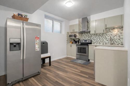 a kitchen with a stainless steel refrigerator and a counter at Bright 2BR Suite Near YYC & Mall in Calgary