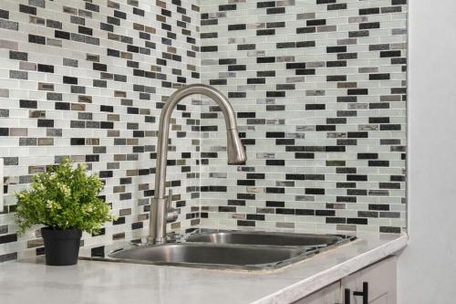 a sink in a kitchen with black and white tiles at Bright 2BR Suite Near YYC & Mall in Calgary