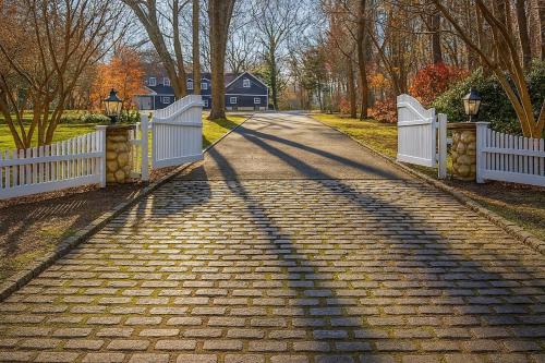 a brick road with a white fence and trees at Luxury 7-Bedroom Villa with Pool in Glen Head in Glen Head