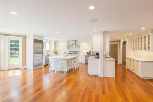 a large kitchen with wooden floors and white cabinets at Luxury 7-Bedroom Villa with Pool in Glen Head in Glen Head