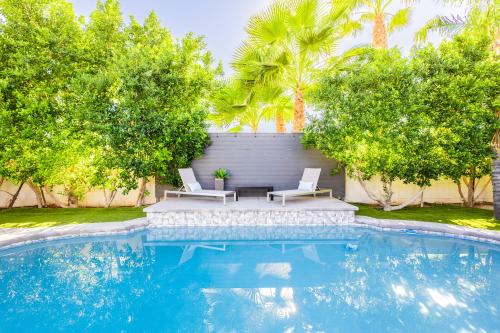 a swimming pool with two white chairs and trees at Luxury Scottsdale Retreat with Heated Pool, Hot Tub, Fire Pit & Game Room & Sleeps 12 in Scottsdale