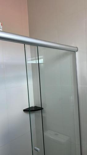 a glass shower door with a shelf in a bathroom at Hotel Serrinha in Botumirim