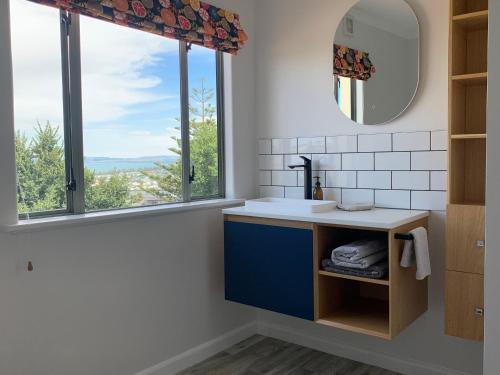 a bathroom with a sink and two windows at Seaview on Sealy Apartment in Napier