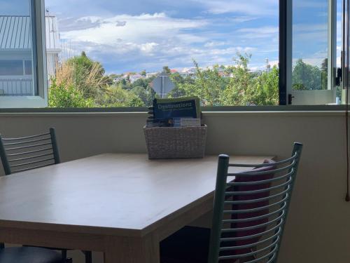 a table and chairs with a table and a window at Seaview on Sealy Apartment in Napier