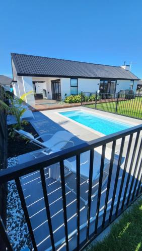 a swimming pool in front of a house at Relaxing coastal home with pool and spa in Papamoa